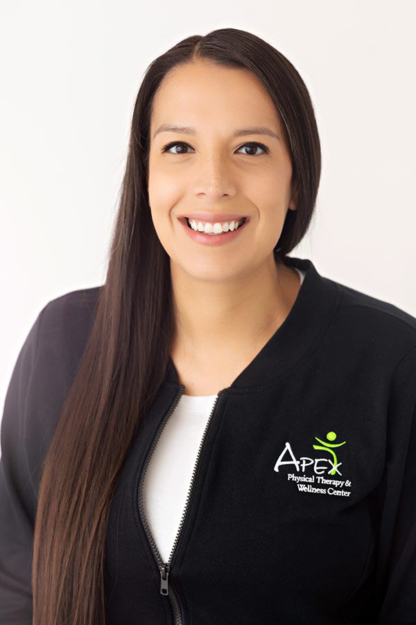 Friendly professional woman, Rachel, smiling in a physical therapy center uniform.