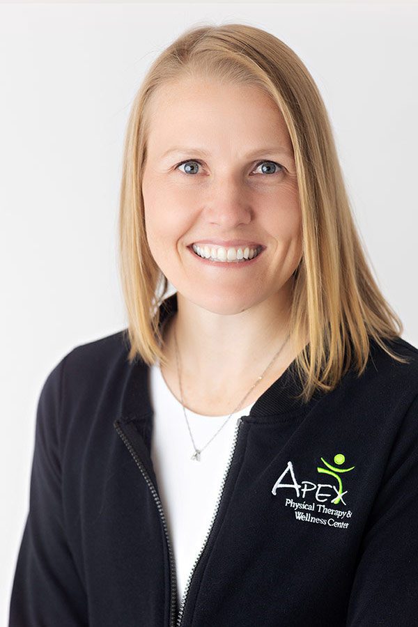 A professional portrait of a smiling woman wearing a jacket with the 