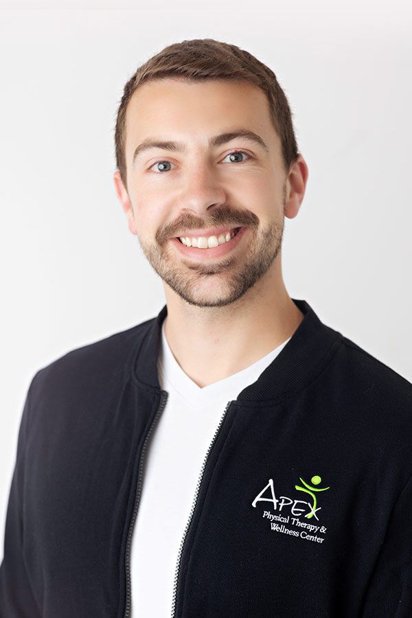 A cheerful man with a beard, dressed in a black zip-up jacket with an 