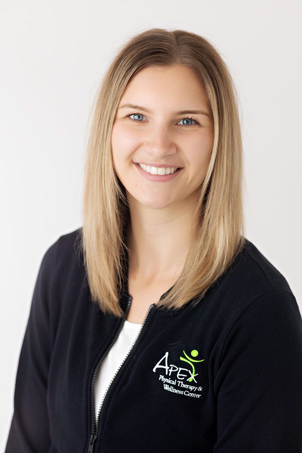A smiling woman with shoulder-length blond hair, wearing a black jacket with the 