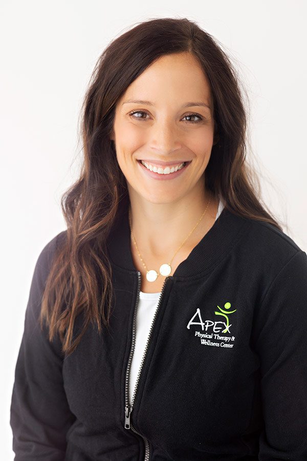 A professional woman with a friendly smile wearing a black jacket embroidered with the 